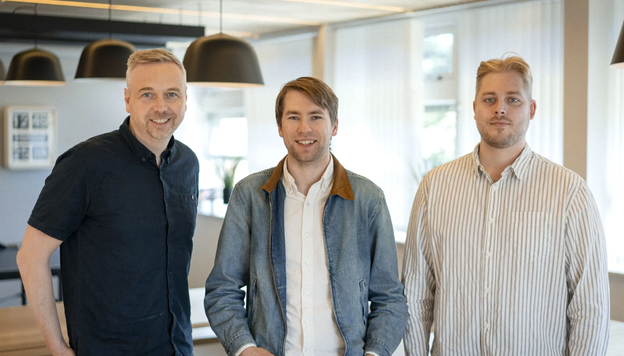 Tre av menneskene bak Utleggsappen, side om side i et lyst kontorlokale